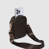 Brown crossbody bag with a phone case on a light gray background