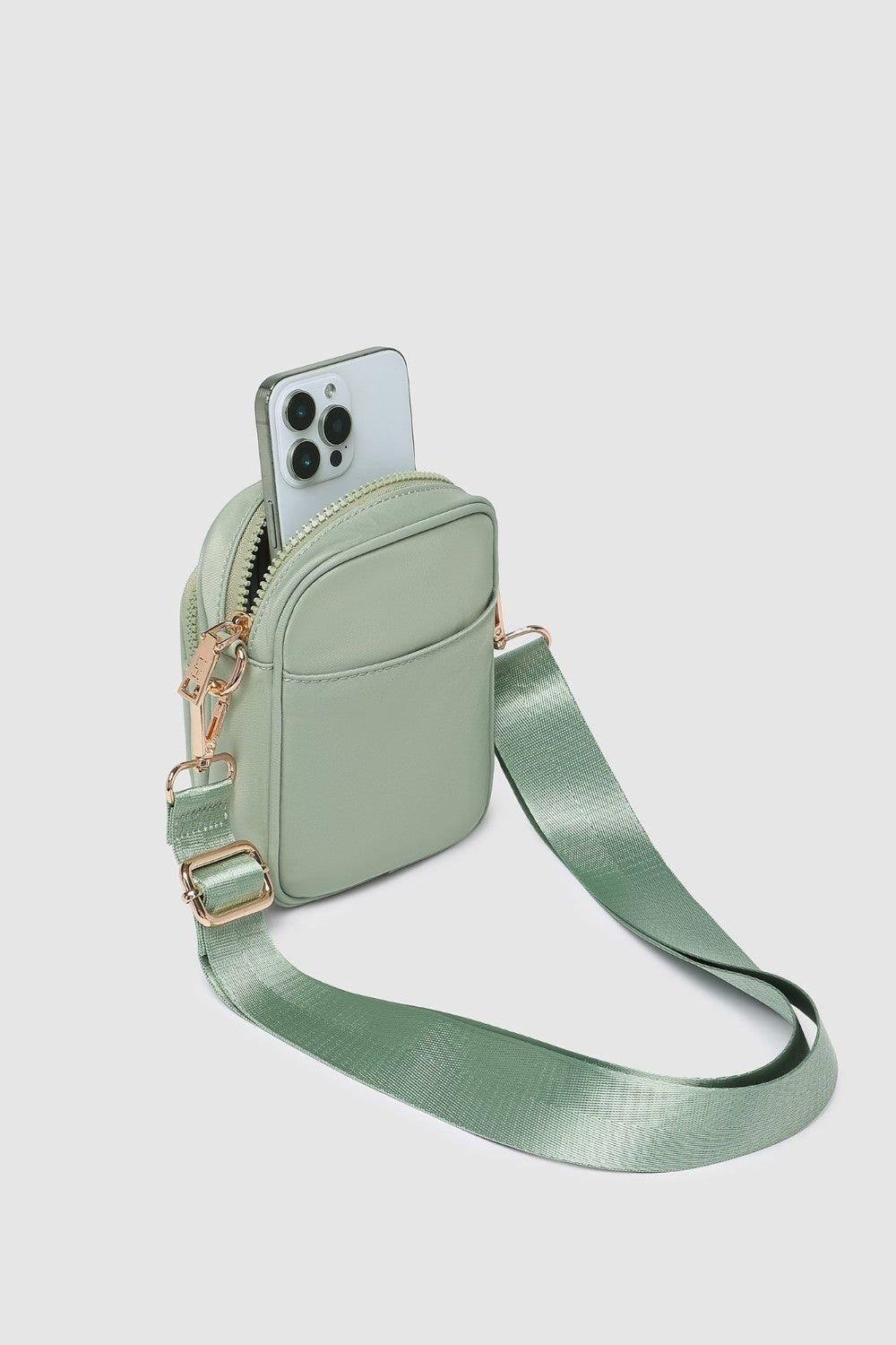Green crossbody bag with a phone pocket on a light gray background