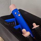 Blue hair straightener with pink handles on a black stand against a neutral background