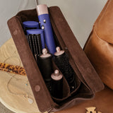 Set of hair styling tools in a brown pleather case on a wooden surface.