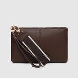 A dark brown leather clutch bag with a matching wristlet strap featuring a white stripe and gold-tone hardware, shown against a light gray background.