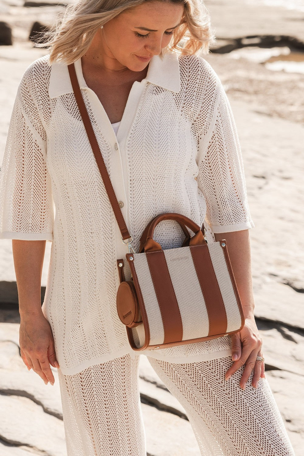 Woman holding a striped handbag on a beach