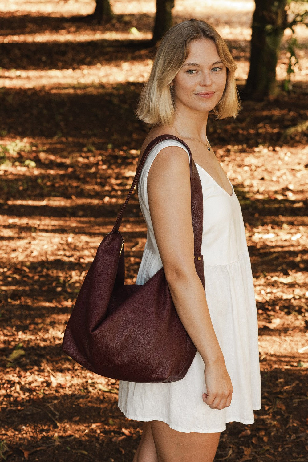 Woman holding a burgundy bag in a forest setting