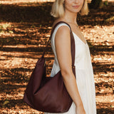 Woman holding a burgundy bag in a forest setting