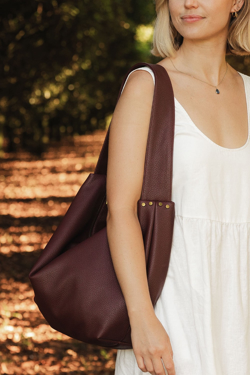 Woman carrying a burgundy pleather bag outdoors