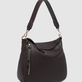 Brown handbag with a strap on a light gray background