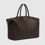 A large brown pebbled leather duffel bag with handles on a light background.