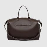 A large brown pebbled leather duffel bag with handles and a detachable strap and an exterior pocket on a light background.