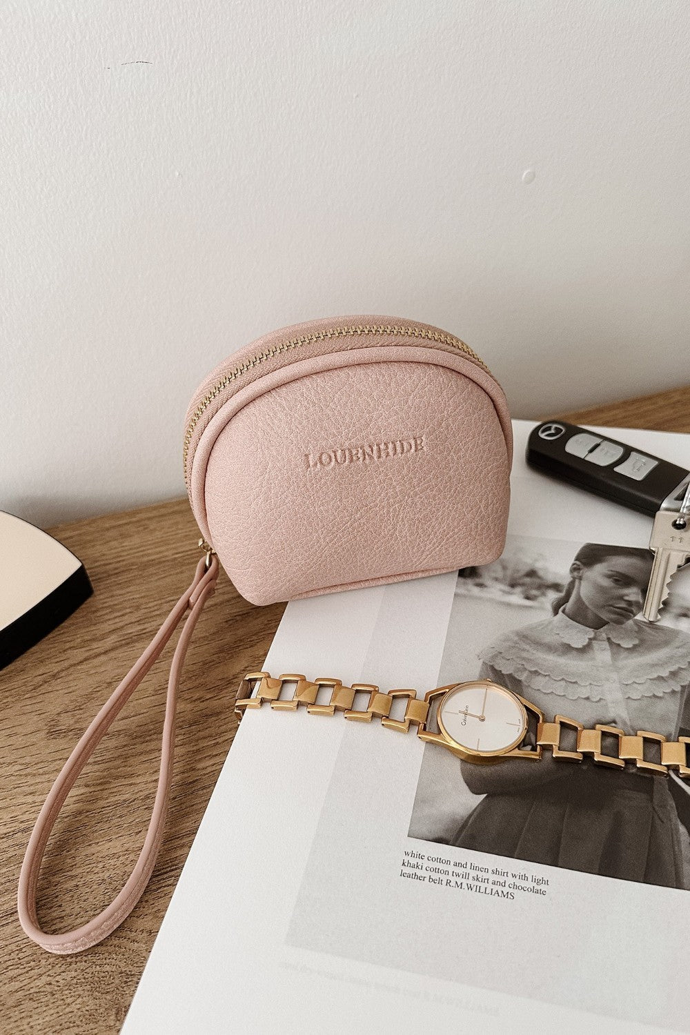 Pink coin purse with strap on a magazine