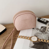 Pink coin purse with strap on a magazine
