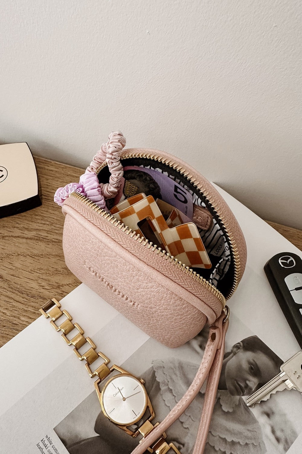 Pink handbag with accessories on a magazine