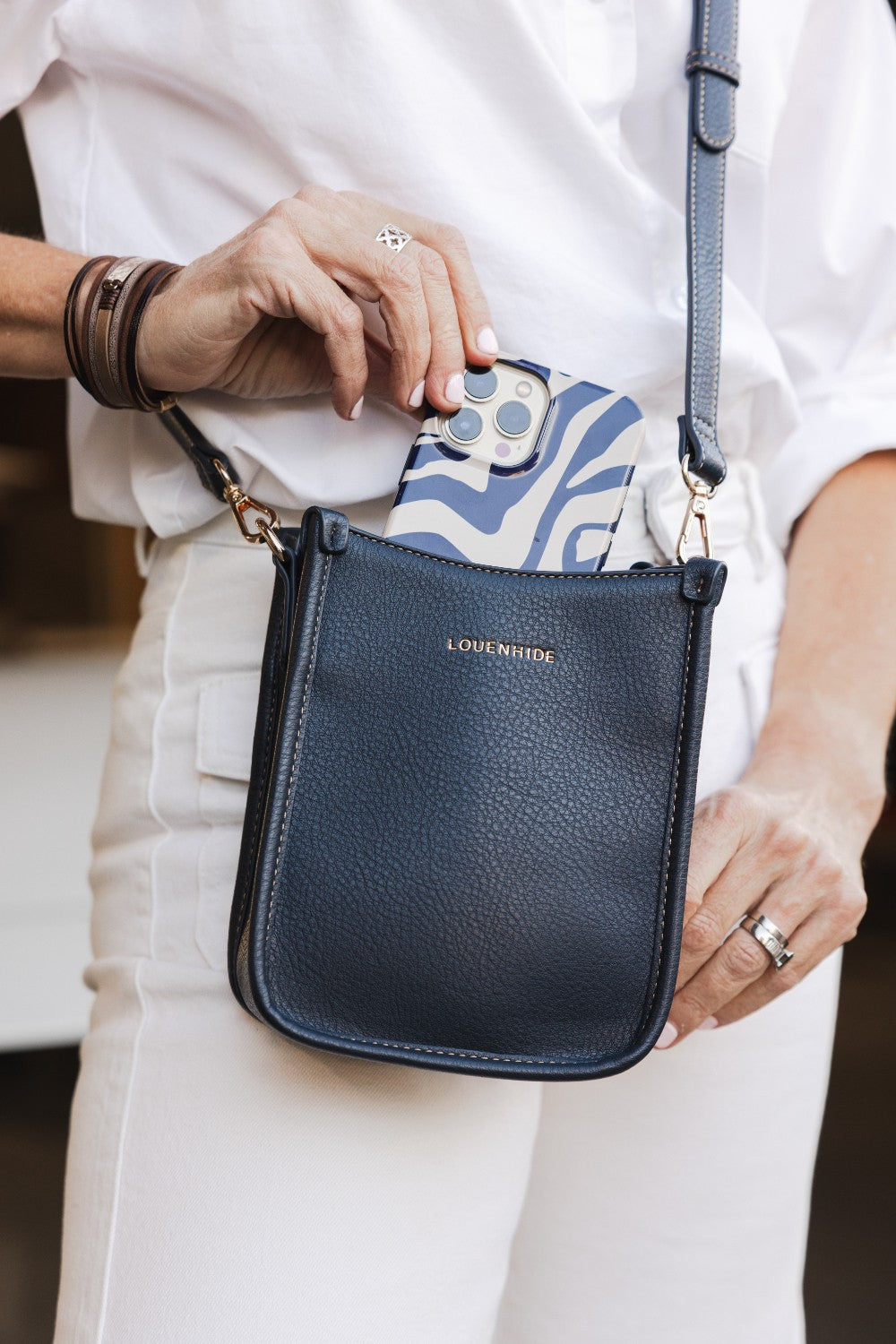 Person holding a navy blue handbag with 'Louenhide' branding.