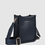 Navy pleather crossbody bag with visible brand name on a light gray background