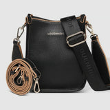 A black pebbled leather crossbody bag with a matching rolled-up strap, gold-tone hardware, and a wide adjustable shoulder strap printed with 'LOUENHIDE' and a star. The brand name 'LOUENHIDE' is embossed on the front.