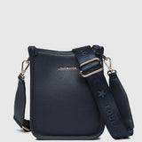 A navy pebbled leather crossbody bag with gold-tone hardware, and a wide adjustable shoulder strap printed with 'LOUENHIDE' and a star. The brand name 'LOUENHIDE' is embossed on the front.