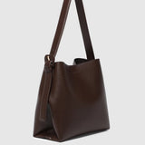 A dark brown leather hobo shoulder bag with a single strap and a subtle embossed logo on the front, shown against a light gray background.