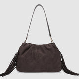 Brown suede handbag with fringes on a light gray background