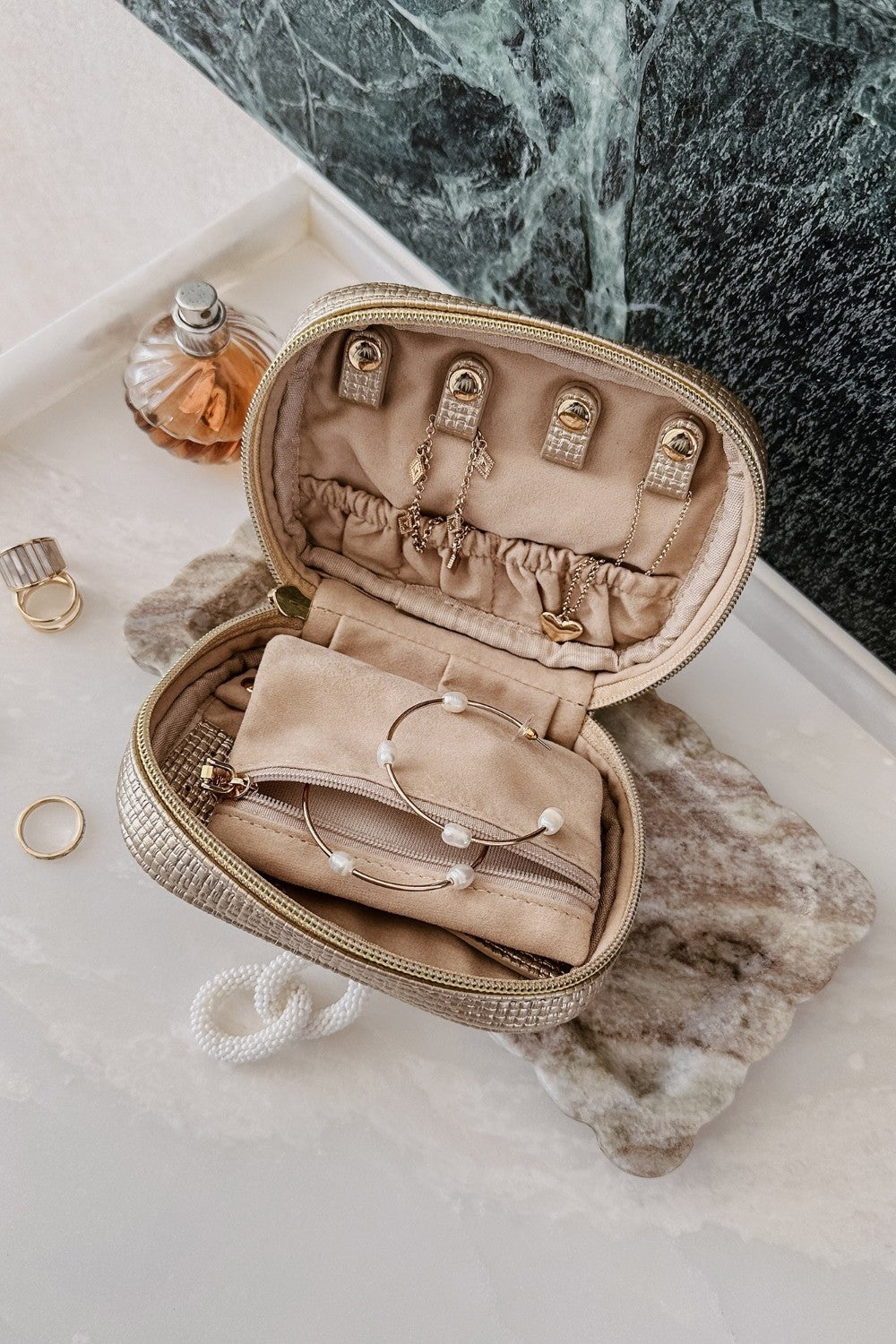 Open champagne coloured jewellery case on vanity setting background