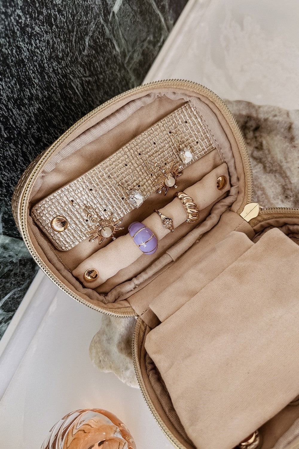 Open champagne coloured jewellery case on vanity setting background