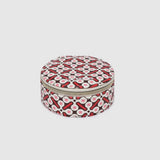 A round zippered jewellery case with a red, black, and white geometric pattern, shown against a solid light gray background.