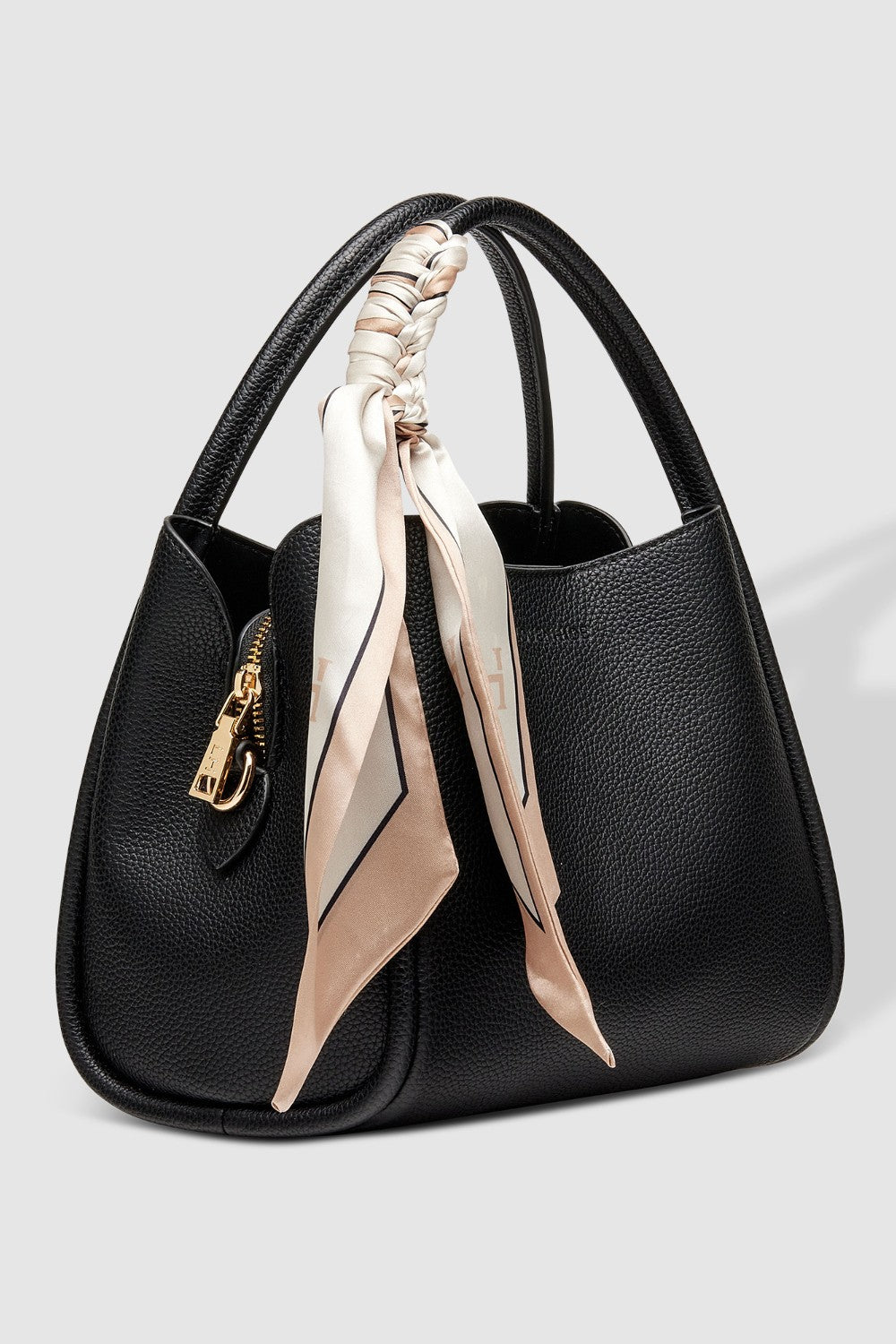 Black handbag with a beige scarf draped over it on a light gray background