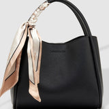 Black handbag with a decorative scarf on a light gray background