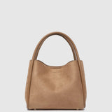 A tan leather handbag with a slouchy, slouchy silhouette and dual top handles, photographed against a solid light gray background.