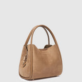 A tan suede shoulder bag with double top handles and a gold-tone zipper pull, shown from a three-quarter angle on a light gray background.