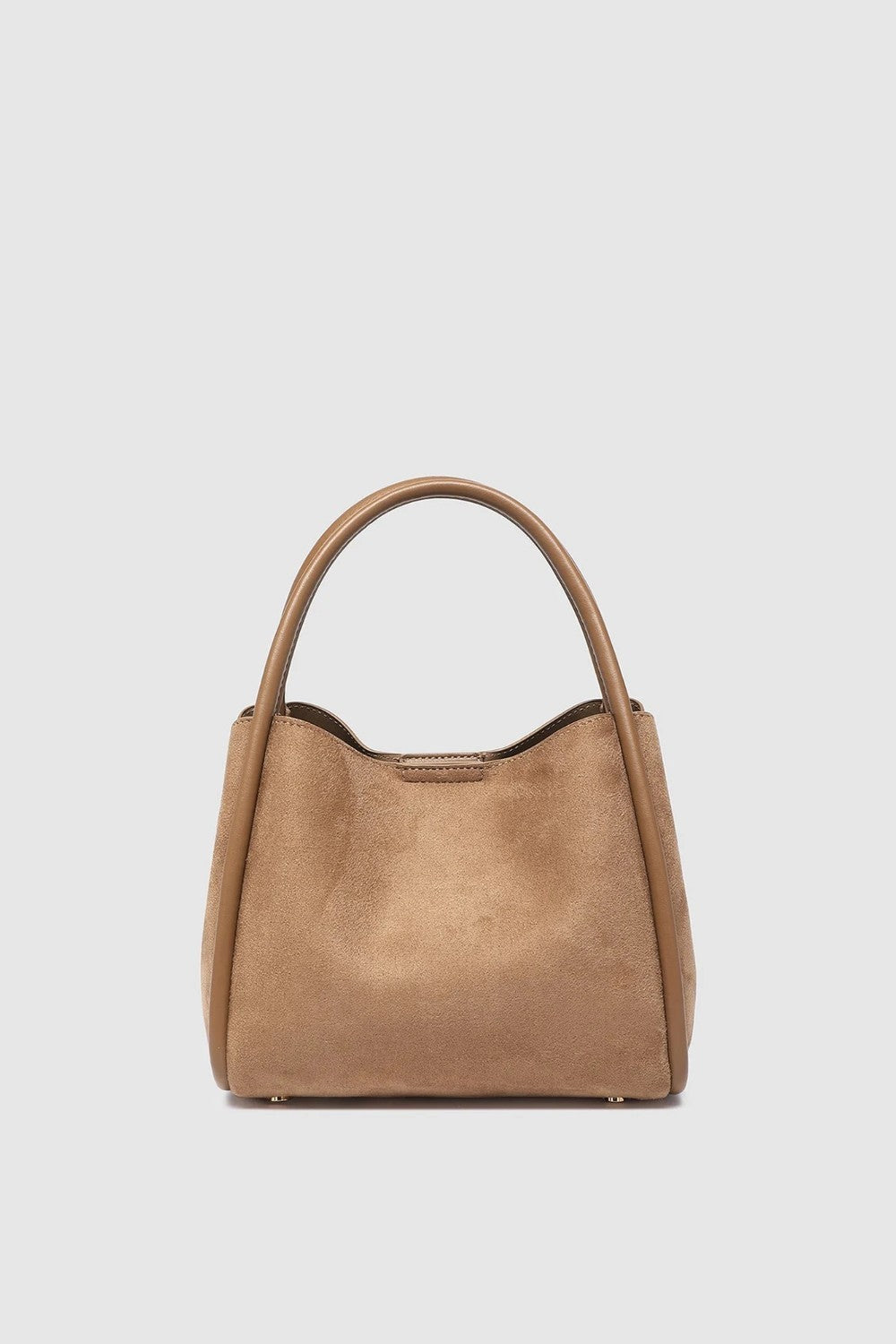 A light brown suede handbag with a top handle, photographed against a solid light gray background.