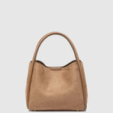 A light brown suede handbag with a top handle, photographed against a solid light gray background.