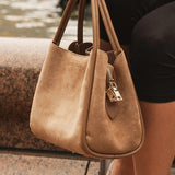 Brown handbag held by a person sitting on steps near water