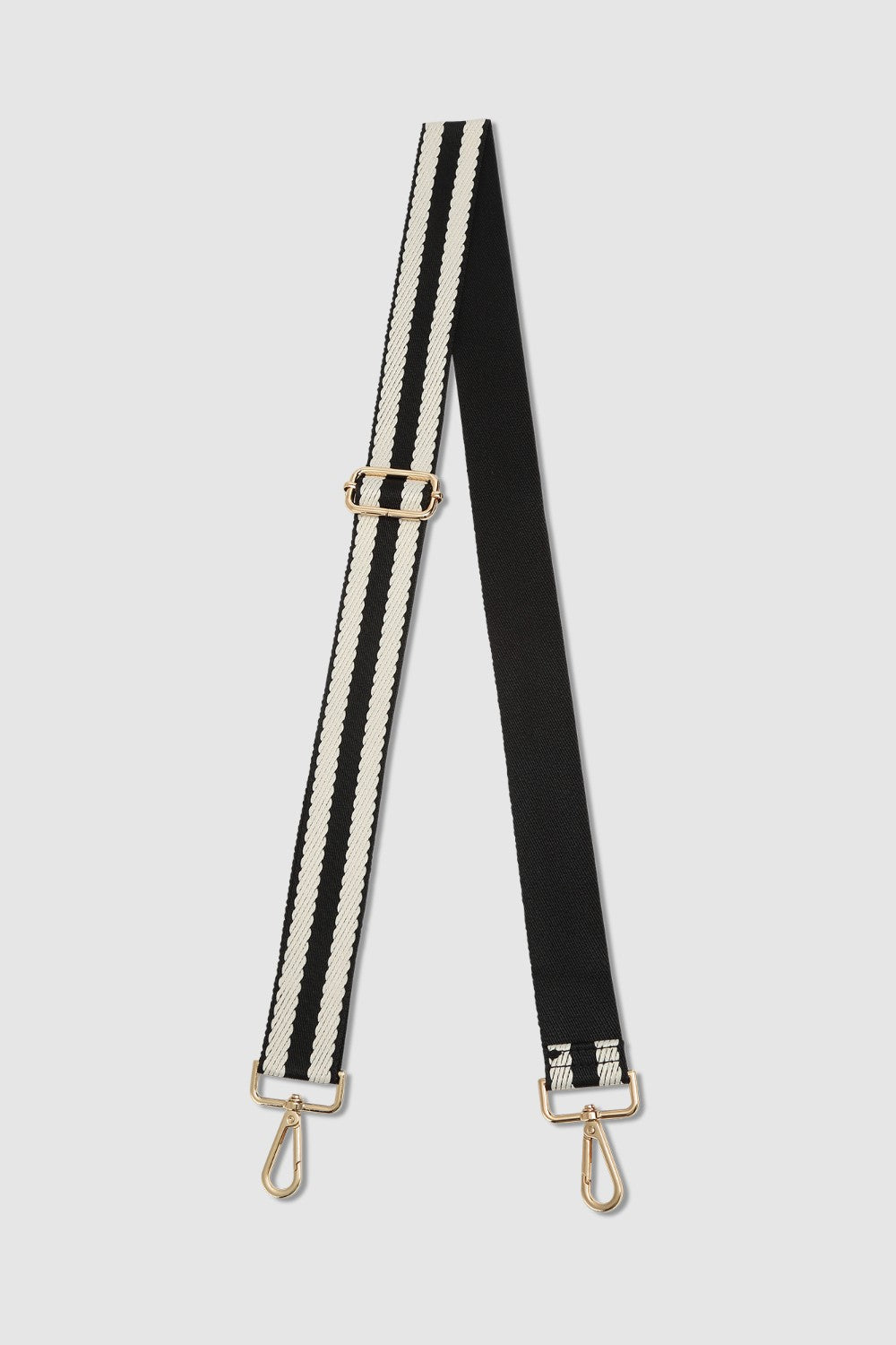 Black and white striped bag strap with gold hardware on a light gray background