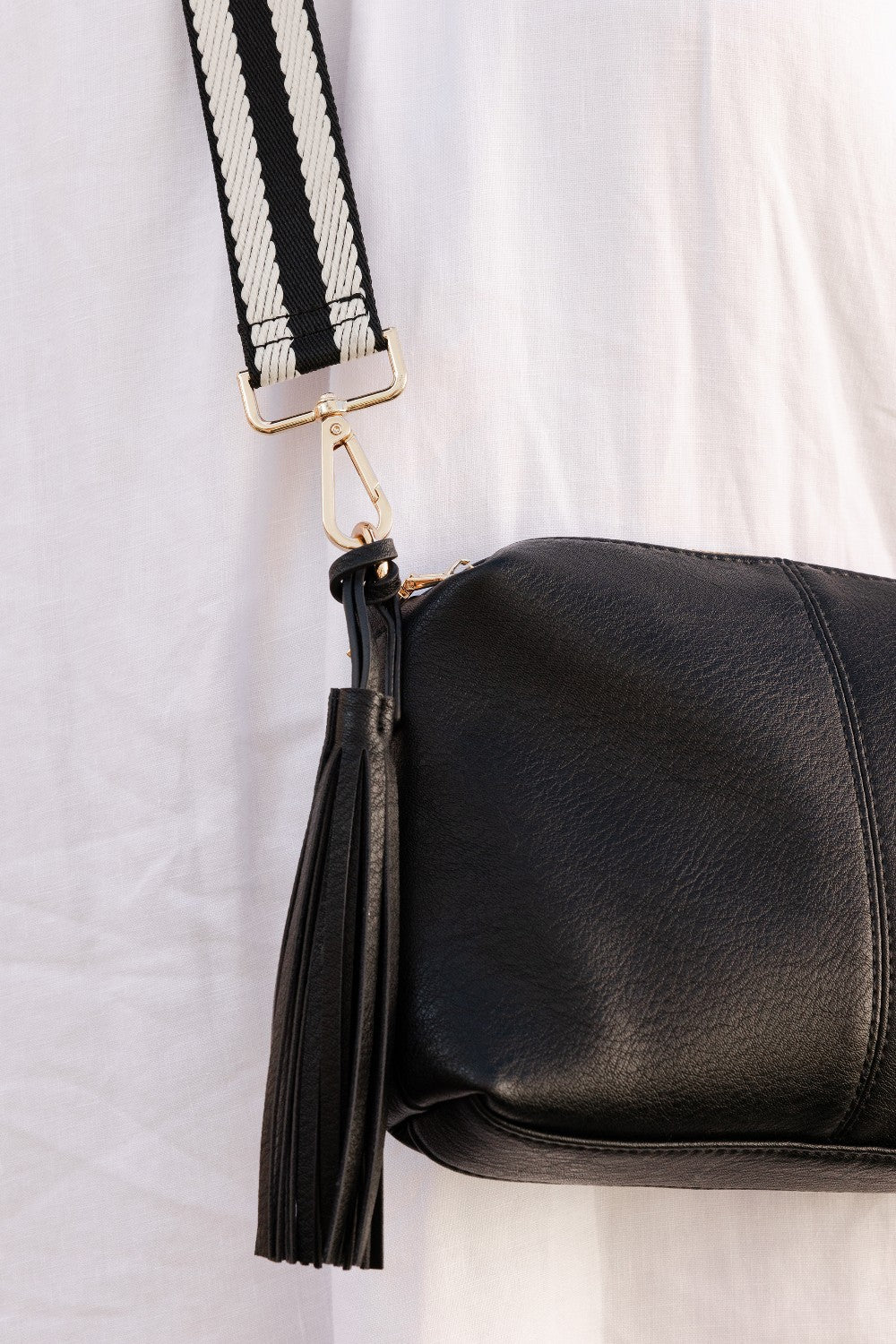 Handbag strap on a bag with a tassel detail on a white background