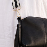 Handbag strap on a bag with a tassel detail on a white background