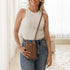 Woman holding a brown crossbody bag in a bright room