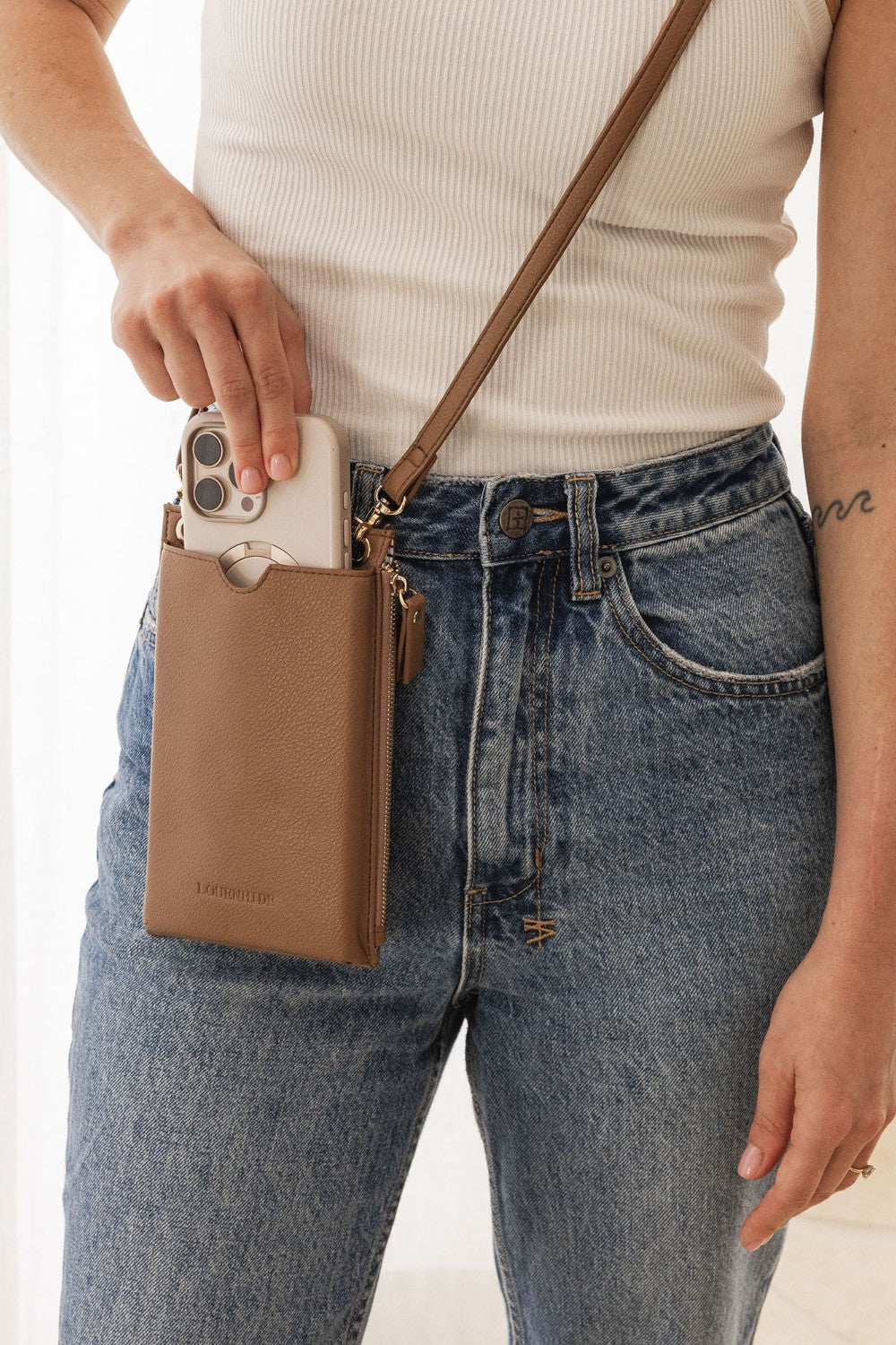Person holding a phone in a brown phone case with a beige background