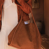 Person holding a brown pleather handbag in a warm-toned indoor setting