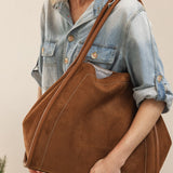 Woman holding a brown pleather tote bag against a neutral background