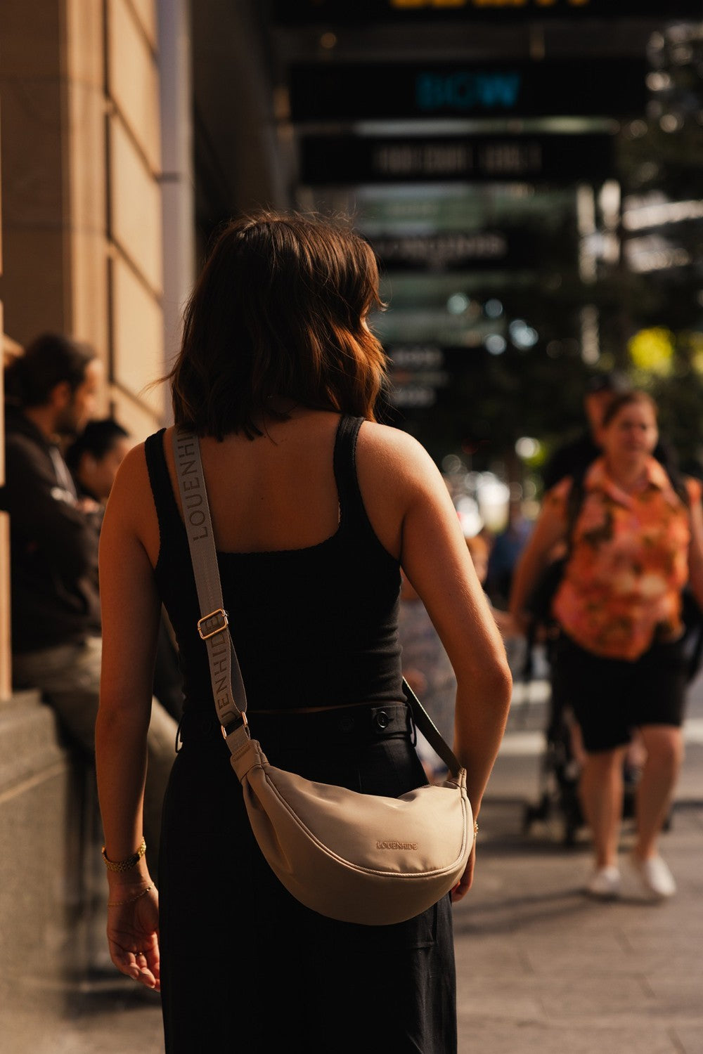 Woman with a beige shoulder bag walking on a city street