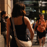 Woman with a beige shoulder bag walking on a city street