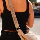 Person wearing a black tank top and carrying a beige crossbody bag with 'LOUENHIDE' branding.