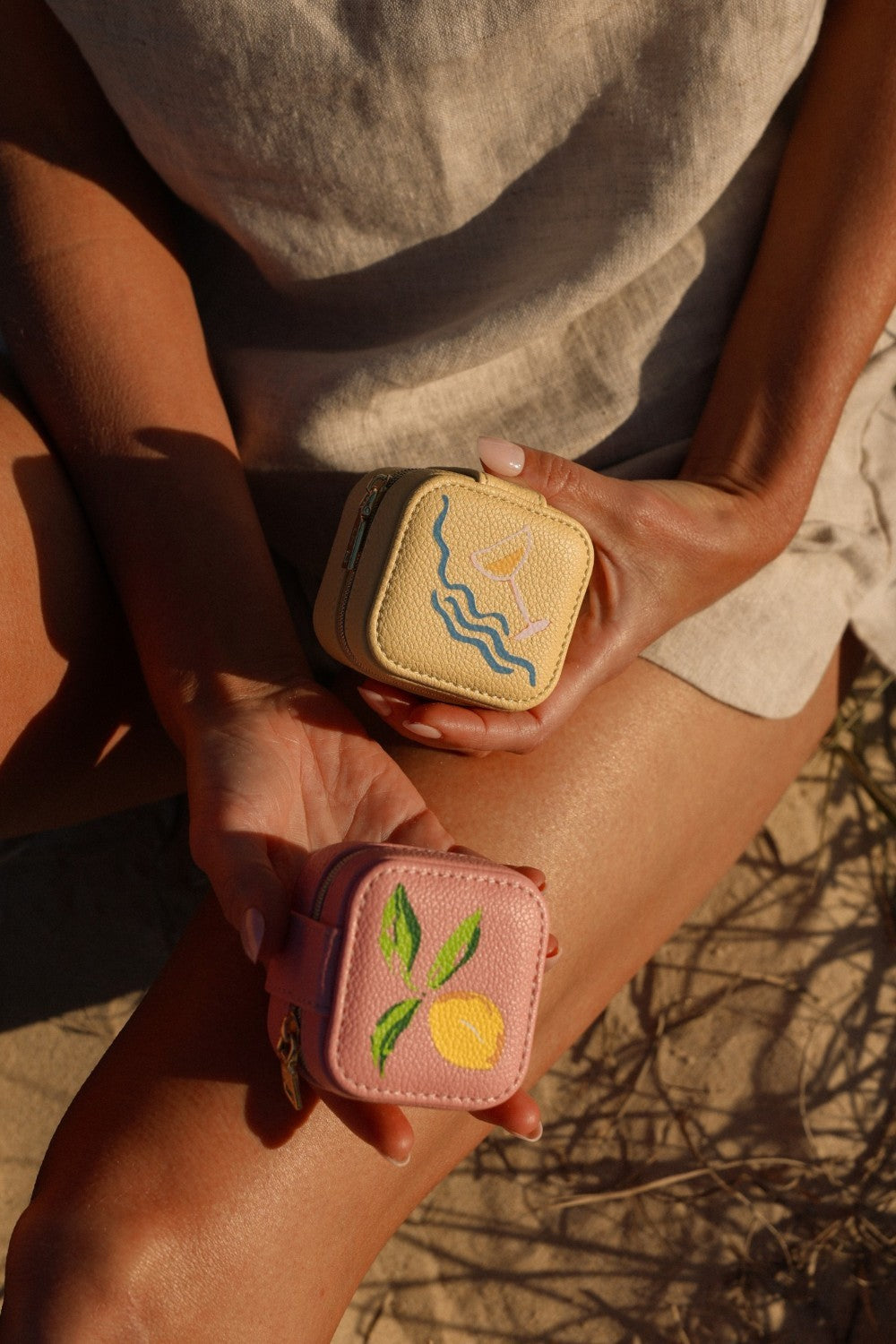 Two small, embroidered pouches held by a person against a natural background.