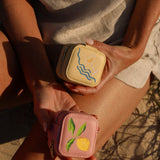 Two small, embroidered pouches held by a person against a natural background.