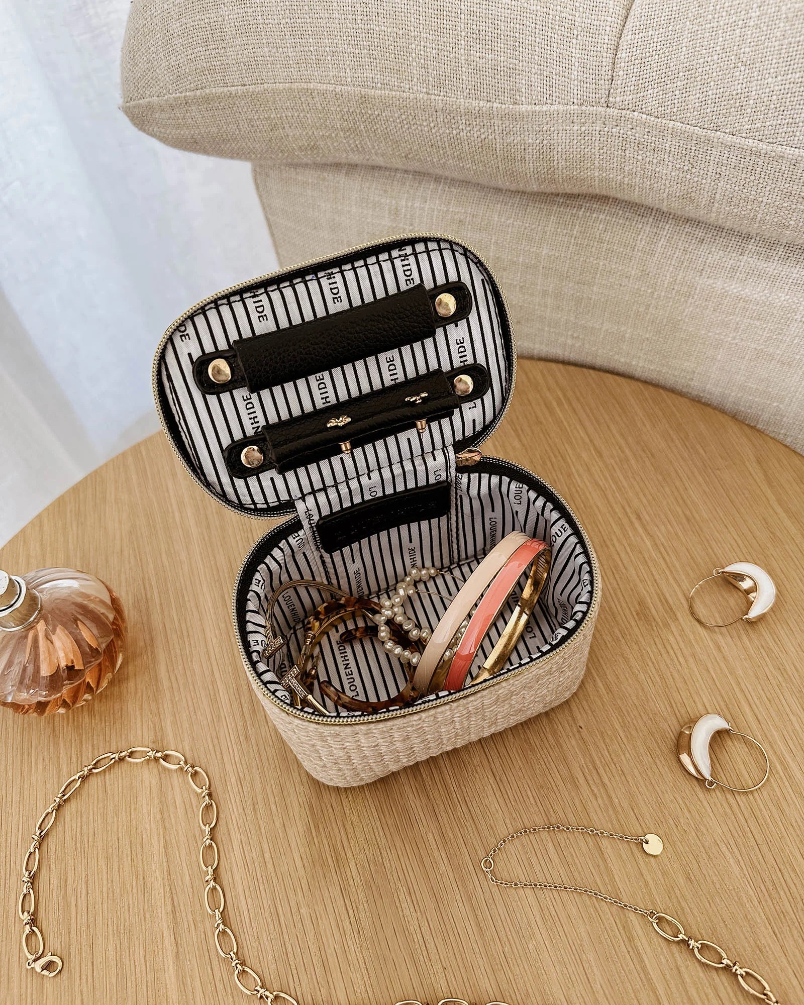 The Louenhide Trudy Jewelry Box is the perfect solution to keeping your valuables safely organized on the go. This compact travel jewelry case fits seamlessly into your luggage without taking up space. The secure zip closure ensures your jewelry stays protected, while the textured raffia and contrasting faux leather exterior add a touch of understated luxury to your travel style. 