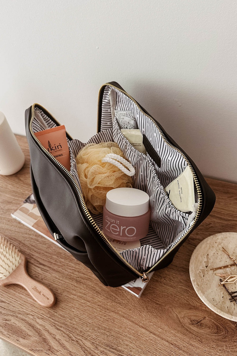 Open makeup bag with skincare products on a wooden surface