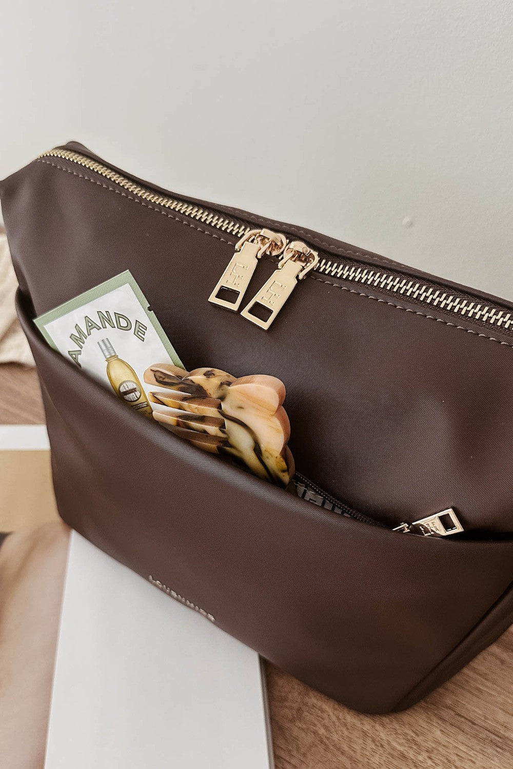 Brown pleather pouch with gold zipper on a wooden surface