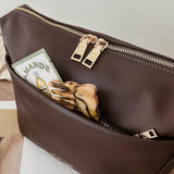 Brown pleather pouch with gold zipper on a wooden surface