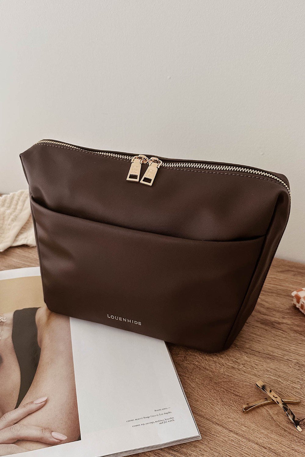 Brown pleather bag on a wooden surface with a magazine underneath