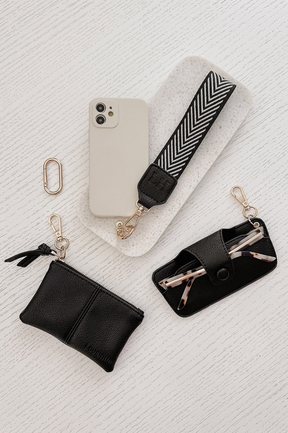 Phone case with strap, keychain, and pouch on a textured white surface