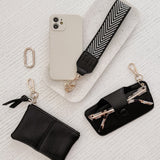 Phone case with strap, keychain, and pouch on a textured white surface